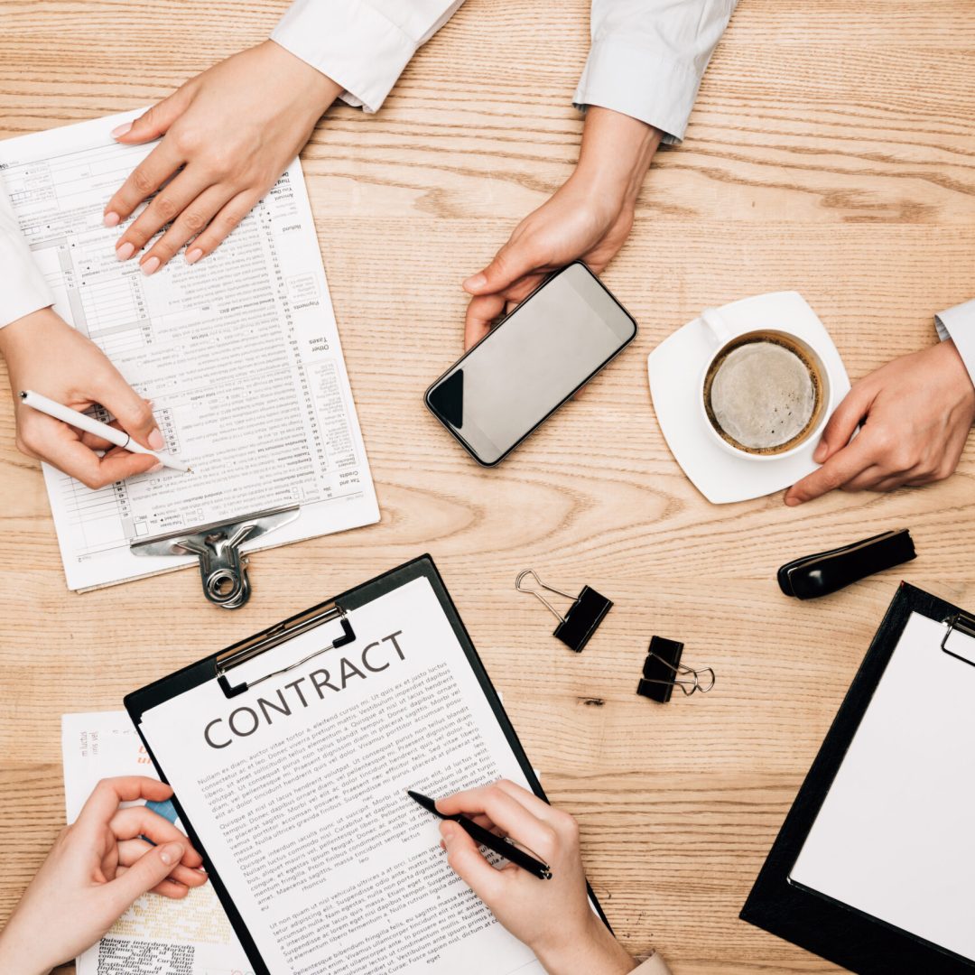 Top view of business partners with contract, paperwork and coffee on wooden table